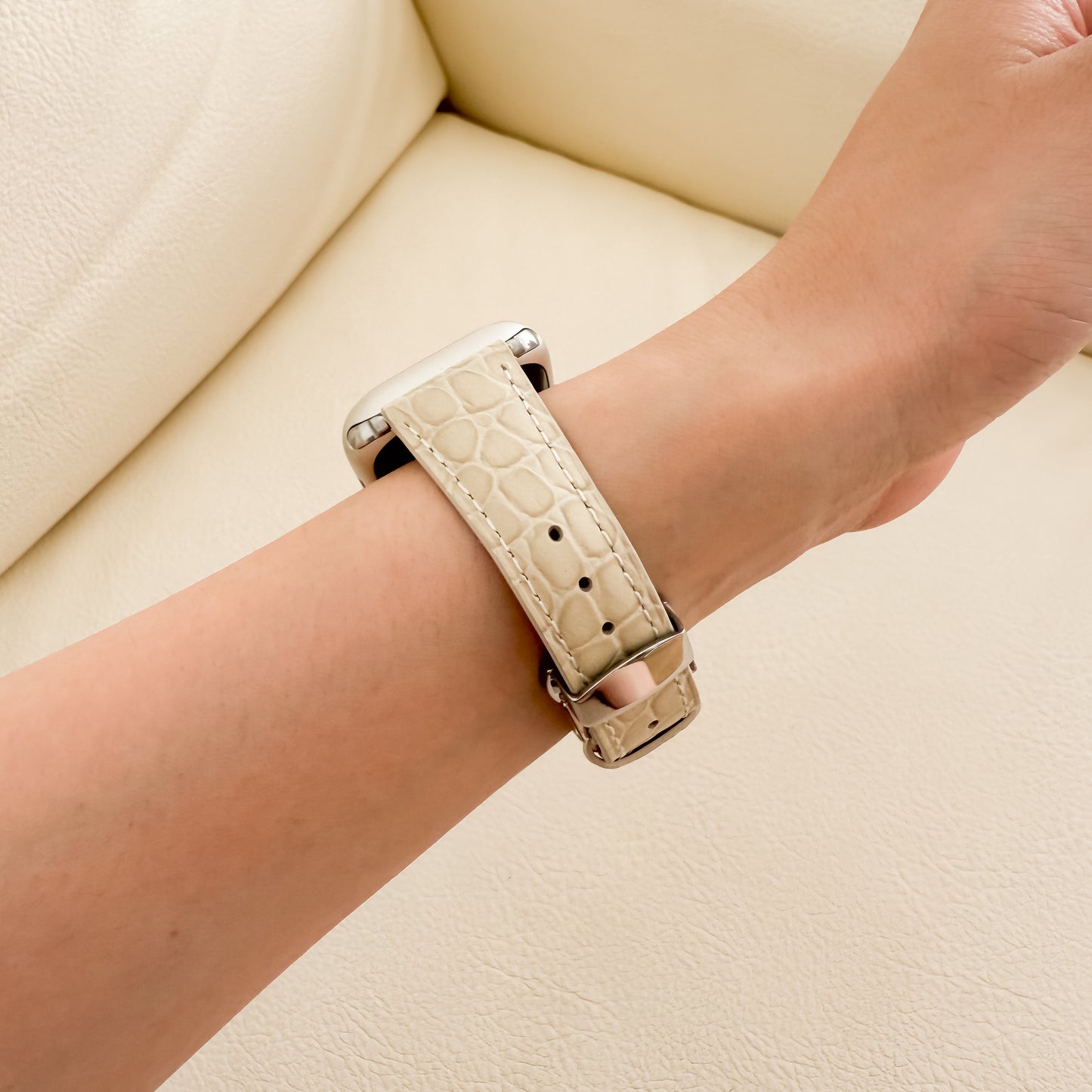 Beige crocodile-patterned watch strap on a wrist 