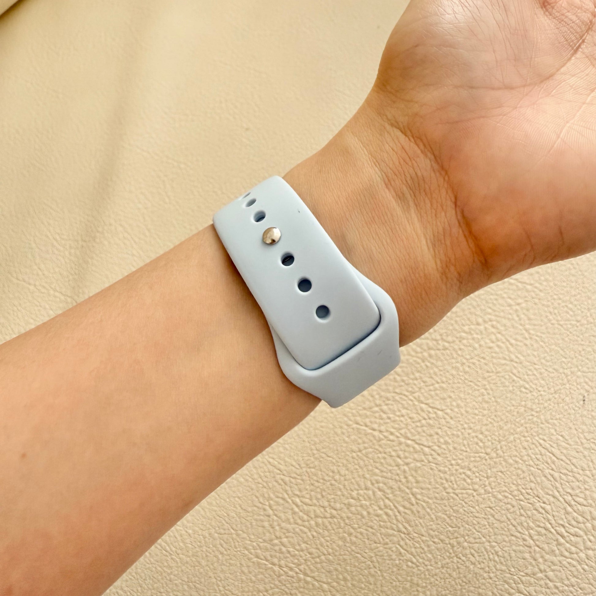 Light blue smartwatch band on a wrist against 