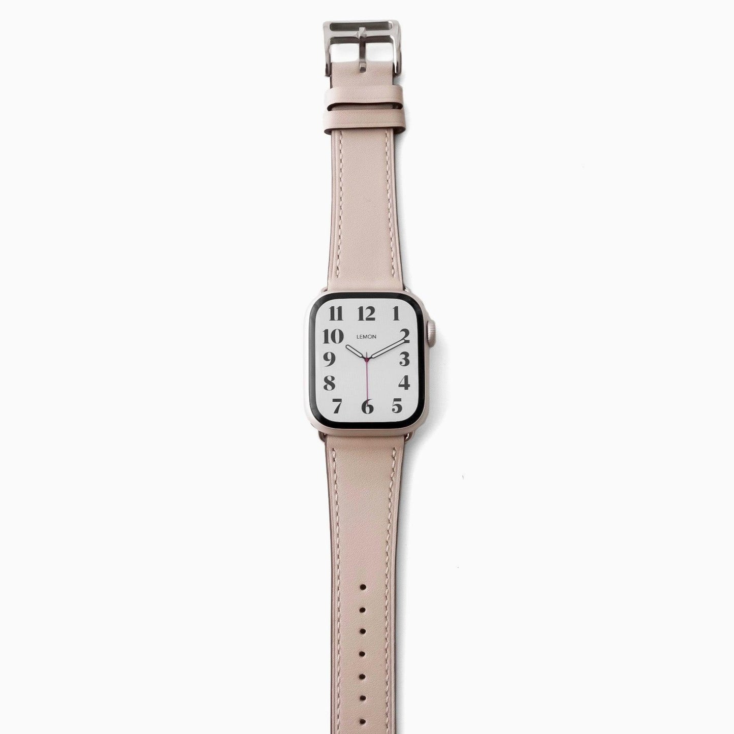A STARLIGHT BEIGE leather Apple Watch band with a silver buckle and a watch face displaying time and date.