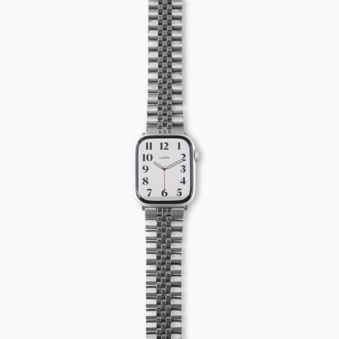 A silver stainless steel band for an Apple Watch with a brushed texture and polished highlights, displayed on a watch.