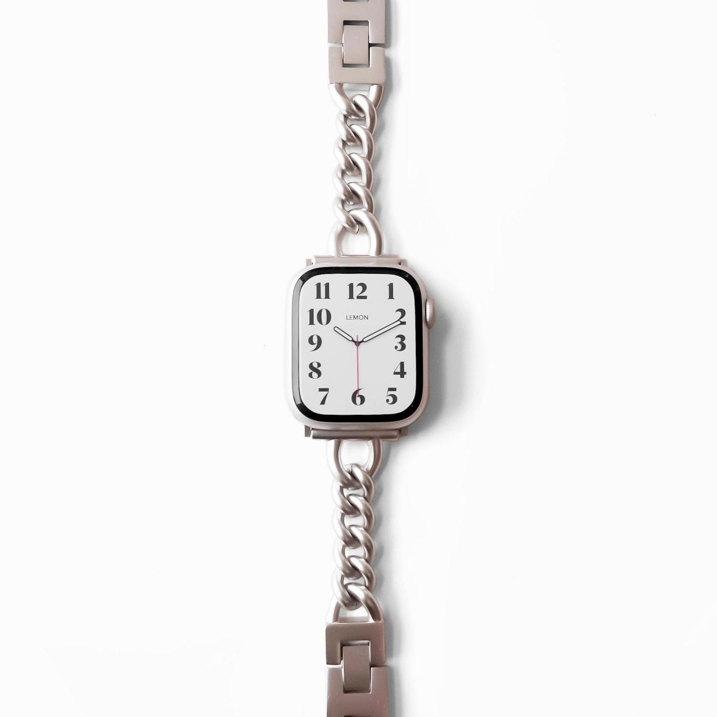 A STARLIGHT-colored metal band Apple Watch bracelet with a starlight finish, displayed alongside a watch face showing time markings.