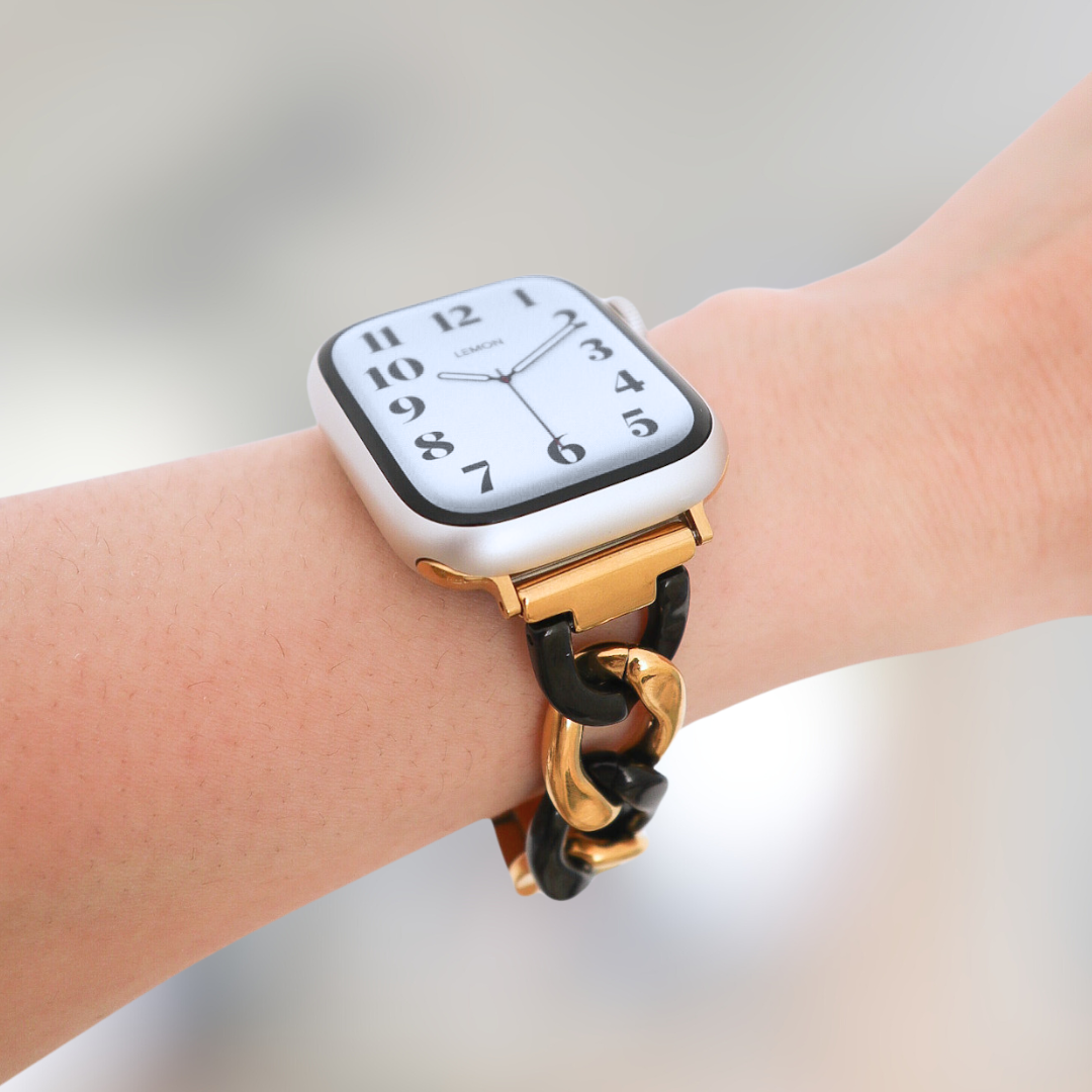 Smartwatch with a gold chain strap on a wrist against a neutral background