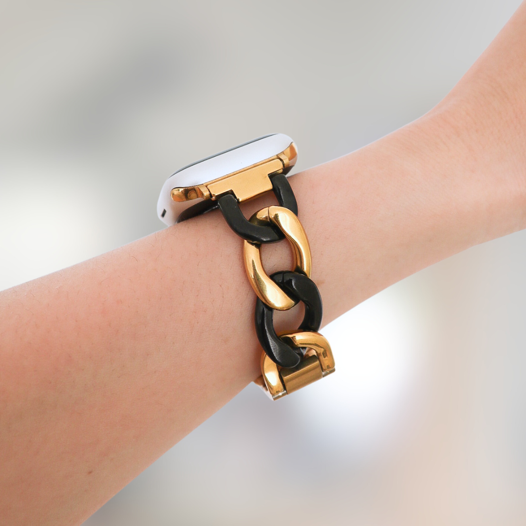 Gold and black chain bracelet on a wrist with a blurred background