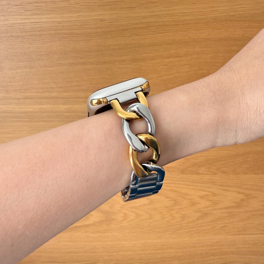 Bracelet with gold, silver links on a wrist against a wooden background